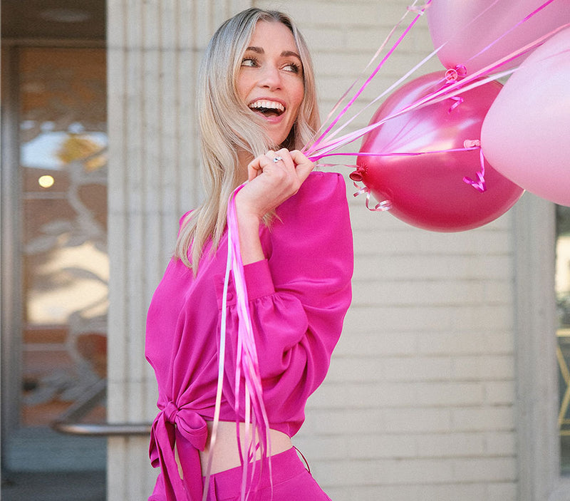 Model holding balloons in a fuchsia cropped blazer for Chloe Colette