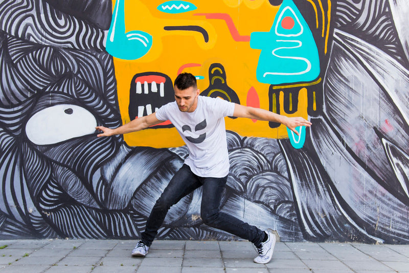 Man in front of a graffiti wall wearing a white T-shirt with the proposed Color Revolution logo